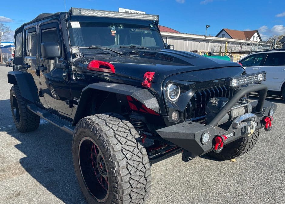 A black jeep with red and white stickers on it's hood.